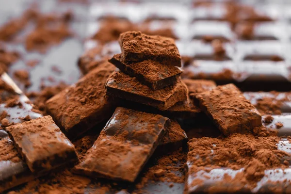 Vista de cerca del cacao en polvo y chocolate sobre fondo oscuro - foto de stock