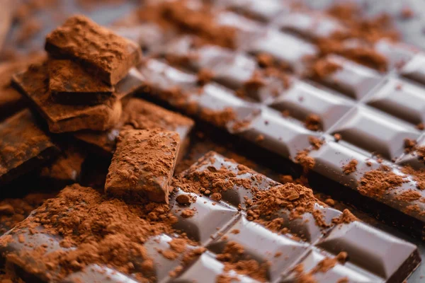 Close up view of dry cocoa powder on chocolate on dark background — Stock Photo