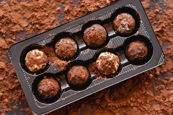 Draufsicht auf Bonbons und unscharfen trockenen Kakao auf schwarzem Hintergrund — Stockfoto