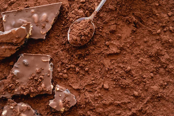 Vue du dessus du chocolat et cuillère sur poudre de cacao sec — Photo de stock