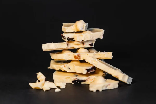 Close up view of pieces of white chocolate with nuts on black background — Photo de stock