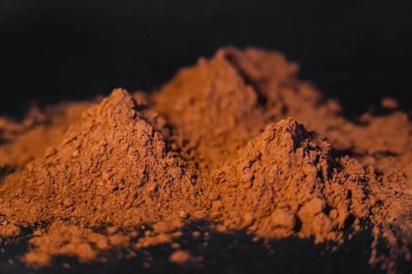 Vista de cerca del cacao seco en polvo sobre fondo negro - foto de stock