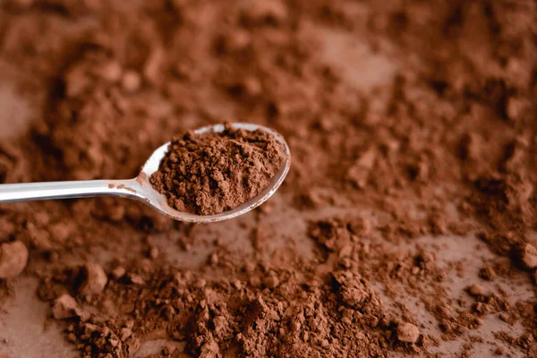 Vista de alto ángulo del cacao en cuchara y sobre fondo marrón - foto de stock