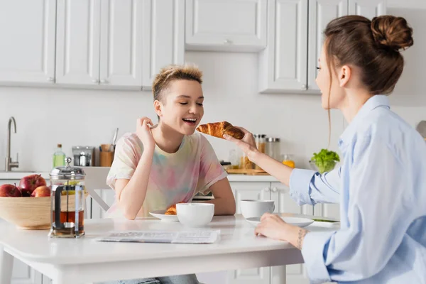 Большой человек кормит любовника вкусным круассаном во время завтрака — стоковое фото