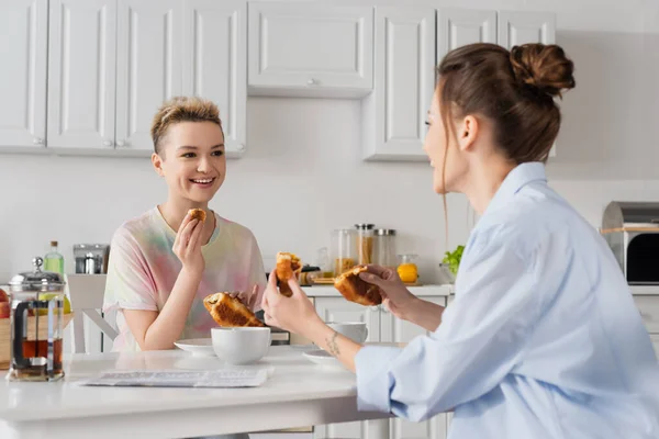 Joyful pansexual couple eating delicious croissants for breakfast — Fotografia de Stock