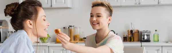 Feliz compañero de alimentación persona pangender con delicioso croissant, bandera - foto de stock