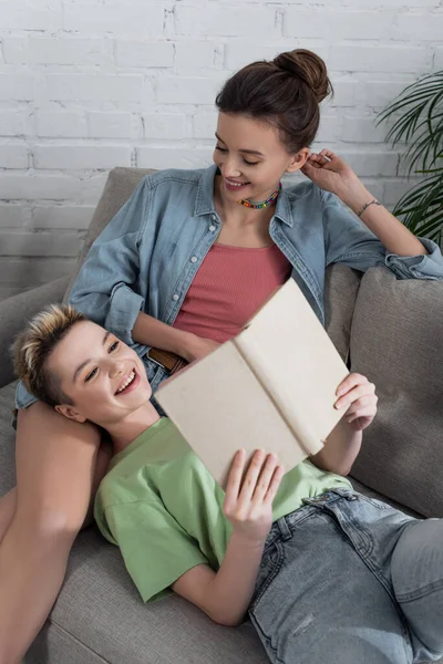 Joyful pansexual person reading novel near young partner — Photo de stock