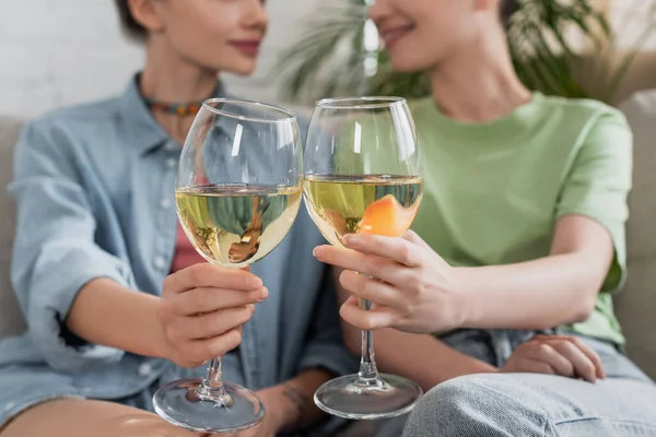 Abgeschnittene Ansicht bigender Partner, die Gläser mit Weißwein auf verschwommenem Hintergrund klirren — Stockfoto