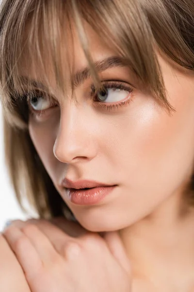 Close up of young woman touching bare shoulder and looking away isolated on white - foto de stock