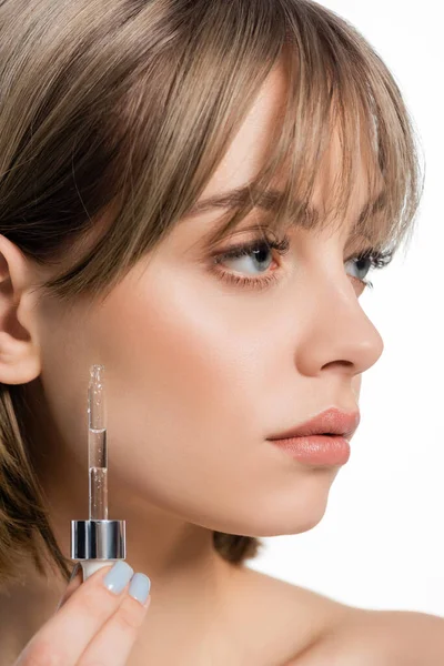 Close up view of young woman with bangs applying serum isolated on white - foto de stock