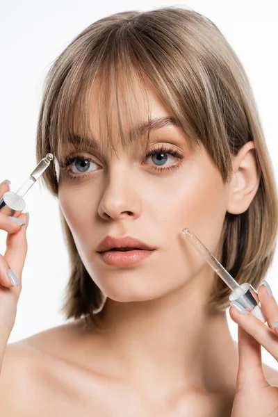 Young woman with blue eyes applying serum with pipettes isolated on white - foto de stock