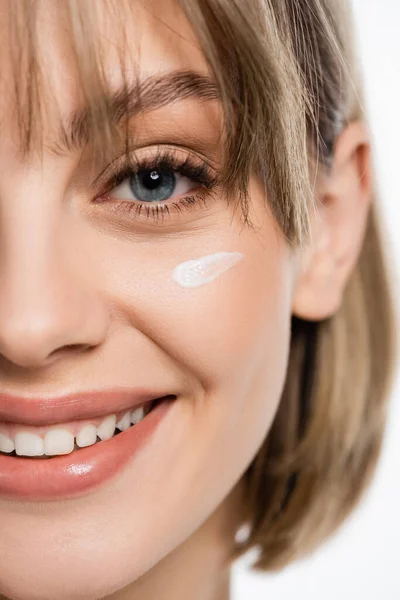 Vista ritagliata di felice giovane donna con frangia e crema sulla guancia sorridente isolato su bianco — Foto stock