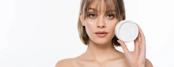 Jeune femme avec frange et crème sur le visage tenant récipient isolé sur blanc, bannière — Photo de stock