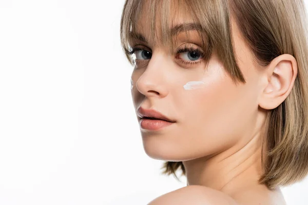 Woman with bangs and cream on cheeks looking at camera isolated on white — Photo de stock