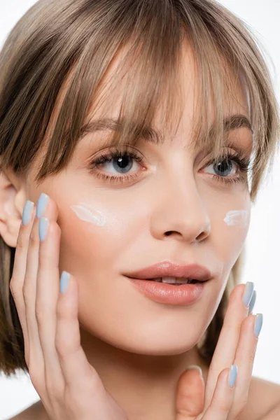 Femme avec frange et crème sur les joues regardant loin isolé sur blanc — Photo de stock