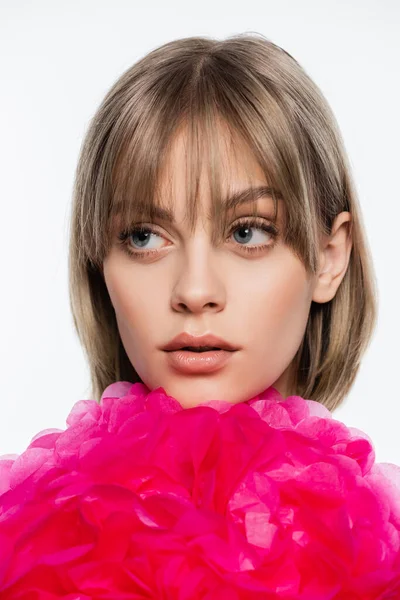 Young woman with bangs looking away near bright pink decorative flower isolated on white — Foto stock