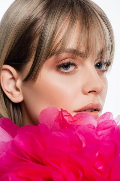 Bonita mujer joven con flequillo cerca flor decorativa rosa aislado en blanco - foto de stock