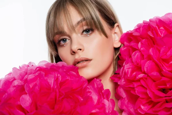 Jovem bonita com strass sob olhos azuis perto de flores rosa isolado no branco — Fotografia de Stock