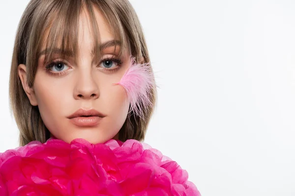 Pretty woman with feather on cheek near bright pink decorative flower isolated on white — Fotografia de Stock