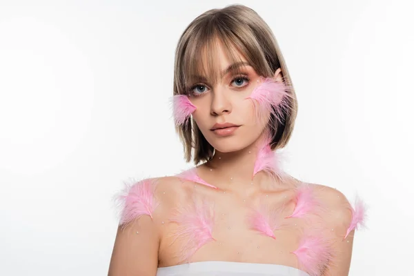 Jeune femme avec des éléments décoratifs et des plumes roses sur le corps et le visage isolé sur blanc — Photo de stock