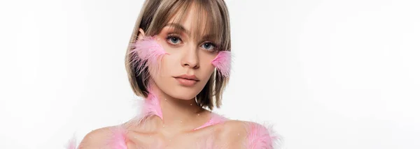 Young woman with decorative elements and pink feathers on face and body isolated on white, banner — стоковое фото