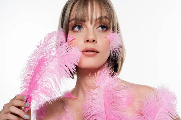 Young woman with decorative beads on body looking away and holding pink feathers isolated on white — Foto stock