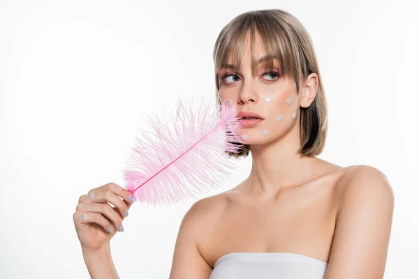 Jeune femme avec des éléments de forme de coeur nacré dans le maquillage tenant plume rose isolé sur blanc — Photo de stock