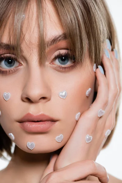 Close up view of young woman with nacreous heart shape elements in makeup isolated on white — стоковое фото