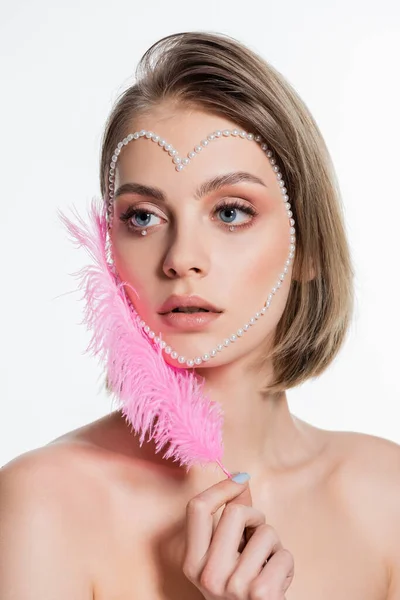 Junge Frau mit kreativen Perlen in Herzform im Gesicht mit rosa Federn auf weißem Grund — Stockfoto