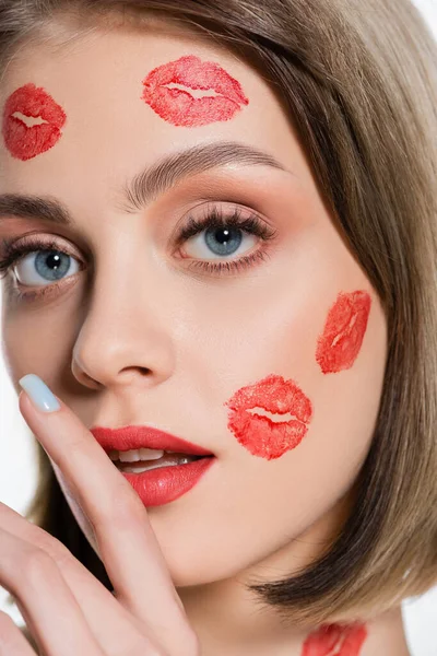 Primer plano de mujer joven con huellas de beso rojo en las mejillas y el cuerpo aislado en blanco - foto de stock