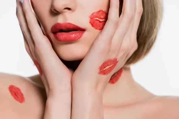 Corte vista de jovem mulher com vermelho beijo impressões no corpo tocando rosto isolado no branco — Fotografia de Stock