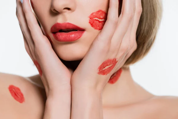 Cropped view of young woman with red kiss prints on body touching face isolated on white — стоковое фото