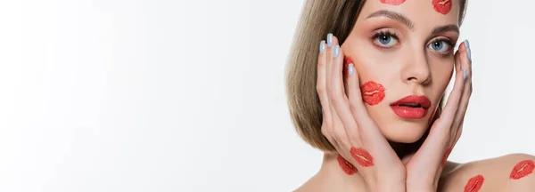 Jovem mulher com vermelho beijo impressões em bochechas tocando rosto isolado no branco, banner — Fotografia de Stock