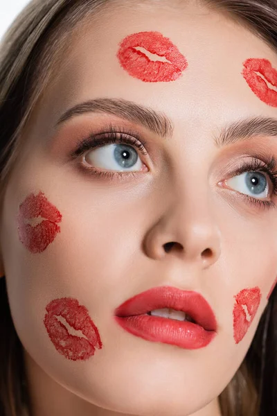 Close up vista de jovem mulher com vermelho beijo impressões em bochechas olhando para longe isolado no branco — Fotografia de Stock