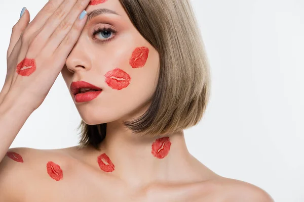 Giovane donna con stampe rosse bacio sulle guance e corpo che copre l'occhio isolato su bianco — Foto stock