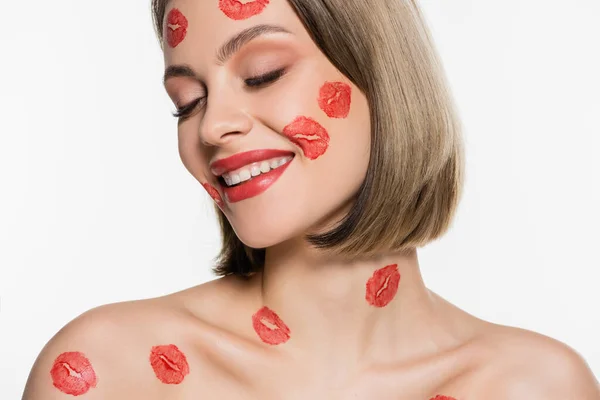 Pleased young woman with red kiss prints on cheeks and body smiling isolated on white - foto de stock