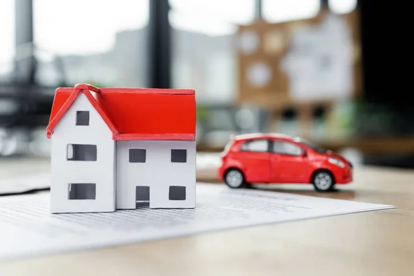Modelo de casa de cartón y coche de juguete en el documento, concepto de impuestos - foto de stock