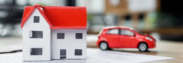 Modelo de casa de cartón y coche de juguete en el documento, bandera - foto de stock