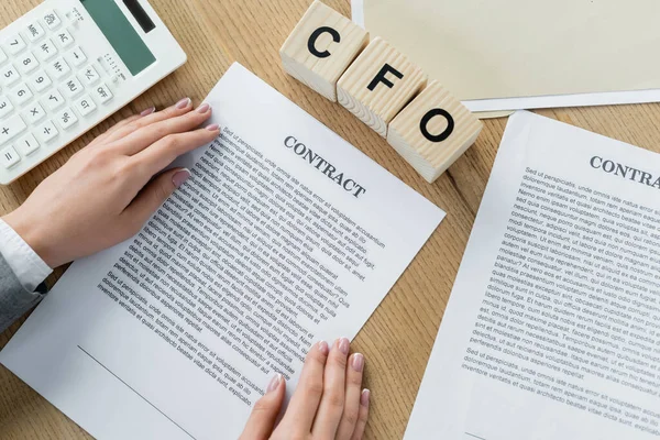 Top view businesswoman holding contact near wooden cubes with cfo lettering and calculator — Stock Photo