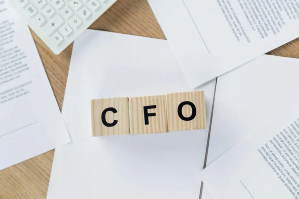 Vista dall'alto di cubi di legno con scritte in cfo su documenti vicino alla calcolatrice — Foto stock