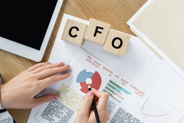 Ansicht des Finanzchefs, der mit Diagrammen in der Nähe digitaler Tablets und Würfeln mit cfo-Schriftzug arbeitet — Stockfoto