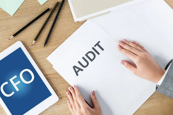 Top view of businesswoman near document with audit lettering and digital tablet with cfo on screen — Stock Photo