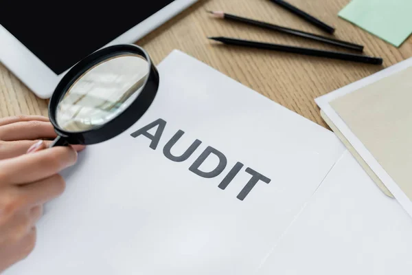Cropped view of woman holding magnifier near audit document — Stock Photo
