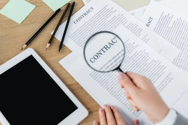 Vista recortada de la mujer sosteniendo lupa cerca del contrato y tableta digital con pantalla en blanco - foto de stock