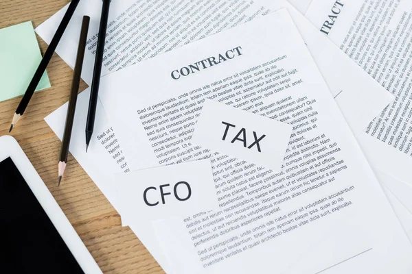 Top view of papers with tax and cfo lettering near contract and digital tablet on desk — Stock Photo