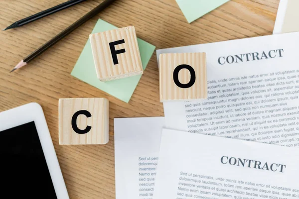 Top view of cubes with cfo lettering near contract wooden pencils and digital tablet on desk — Stock Photo