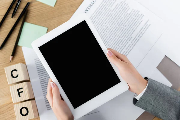 Cropped view of businesswoman holding digital tablet with blank screen above papers with contract and cfo letters on cubes — Stock Photo