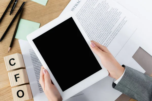 Vista recortada de la mujer de negocios sosteniendo tableta digital con pantalla en blanco por encima de los papeles con contrato y letras cfo en cubos - foto de stock