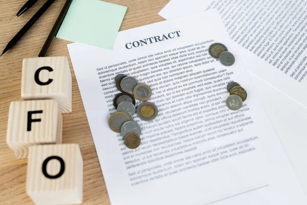 Vista superior de cubos de madeira com letras cfo perto de moedas no contrato — Fotografia de Stock