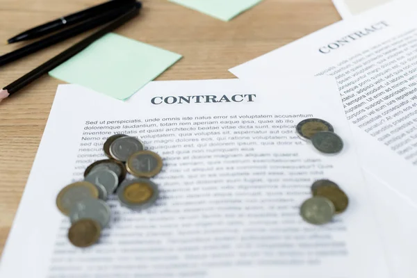 Monedas de plata y oro en contrato cerca de bolígrafos - foto de stock